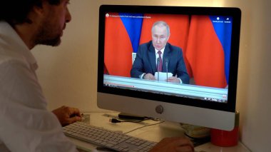 Avrupa, Milan 2023 - Rusya ile Ukrayna arasındaki savaş hakkında dizüstü bilgisayarında televizyon haberleri izlemek - Putin ulusa sesleniyor