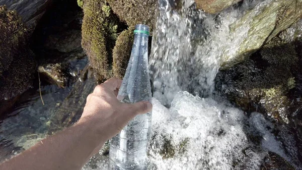 filling the water bottle in a mountain stream - glacier thaw and drinking water in the river - no plastic use and eco-friendly choice for the environment - Save the Planet