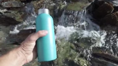 Su şişesini bir dağ deresinde doldurmak - nehirde buzul çözülmesi ve içme suyu - plastik kullanım yok ve çevre için çevre dostu tercih - Gezegeni Kurtarın