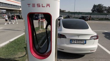 Tesla elektrikli otomobil şehrin merkezindeki modern bir elektrik şarj istasyonunda bataryasını şarj ediyor - yeni sürdürülebilir elektrik hareketliliği - küresel ısınma