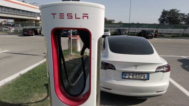 Tesla elektrikli otomobil şehrin merkezindeki modern bir elektrik şarj istasyonunda bataryasını şarj ediyor - yeni sürdürülebilir elektrik hareketliliği - küresel ısınma