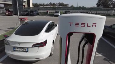 Tesla elektrikli otomobil şehrin merkezindeki modern bir elektrik şarj istasyonunda bataryasını şarj ediyor - yeni sürdürülebilir elektrik hareketliliği - küresel ısınma