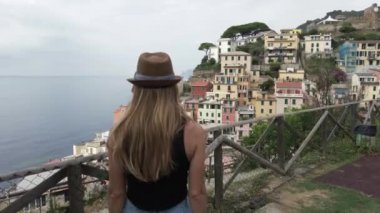 Avrupa, İtalya, Liguria, Cinque Terre Riomaggiore - Dünyanın dört bir yanından gelen turistler için Cinque Terre turistik merkezini ziyaret eden şapkalı kız turist - turist -