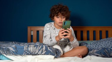 9 yaşındaki çocuk, yatak odasında oturup akıllı telefona, sosyal ağlara ve internete olan bağımlılığına bakmaktan mutlu. Günlük hayatta çok fazla zaman harcıyor.
