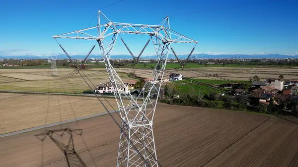 High voltage pylon for the transport of electricity and houses with solar panels close to Milan in Lombardy Italy Europe - green revolution, Save the planet and climate change - increase energy cost