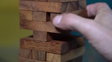 İnsanın eli odun parçalarıyla inşaat blokları oynuyor - evde boş zamanlarında yaratıcı eğlence için oyunlar - denge ve zeka egzersizi