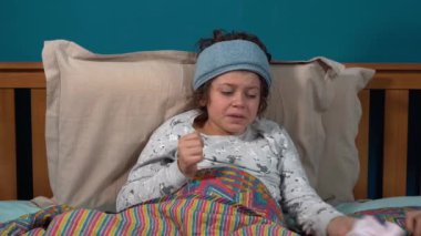 Yatağında termometresi olan hasta çocuk.