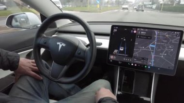 Avrupa, İtalya, Milan 12-11-2023 Otomatik pilot ve Tesla Electric araba - araba şehir trafiğinde ilerliyor, sürücü ellerini direksiyon destekli direksiyon ekranı yapay zeka ekranına koymuyor
