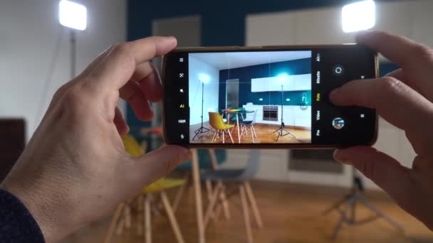 房地产摄影师在公寓客厅里的房子里用智能手机拍照和录像 与房地产经纪人一起卖房子 并在家里布置室内设计 — 图库视频影像