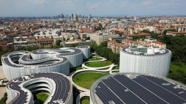 Çatıdaki güneş panellerinin havadan görüntüsü. Yeni SDA Bocconi kampüsü, Yönetim Okulu. Sınıfları olan modern bir bina. Yeşil Devrim Ekolojik Enerji. Milan Skyline, İtalya Avrupa