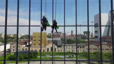 Avrupa, İtalya, Milan. Modern gökdelen binası ve havada asılı duran iki pencere temizleyicisi. 