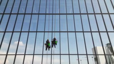 Avrupa, İtalya, Milan. Modern gökdelen binası ve havada asılı duran iki pencere temizleyicisi. 