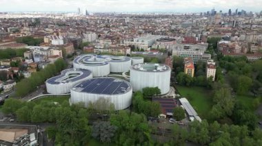 Yeşil ağaçlarla çevrili modern beyaz binalar.