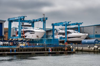 2 different model yachts held on outside gantries at the main Sunseeker manufacturing facility in Poole quay, dorset clipart