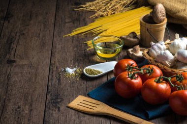 Spagetti, domates, mantar, kekik ve ahşap bir masaya yerleştirilmiş çeşitli baharatlar gibi spagetti yapmak için çeşitli malzemeler..