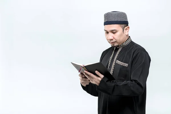 肖像画アジアのイスラム教徒の男が立ってクルアーンを読んで 高く評価します クルアーンのアラビア語の書道の意味を持つ聖アル クルアーン 黒の背景に コピースペースと — ストック写真