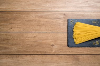 Spagetti, ahşap bir masaya yerleştirilmiş siyah bir taş tabağa konur..