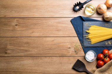 Spagetti, domates, kekik otu gibi çeşitli malzemeler ve ahşap bir masaya yerleştirilmiş çeşitli baharatlar, fotokopi alanı, üst görünüm gibi..
