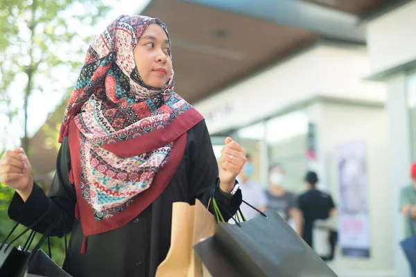 一位亚洲穆斯林妇女提着一袋她一直在购买的商品 买了许多面带笑容的商品 — 图库照片