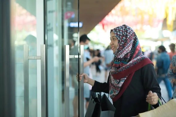 一位亚洲穆斯林妇女提着一袋她一直在购买的商品 买了许多面带笑容的商品 — 图库照片