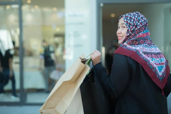 stock image An Asian Muslim woman is carrying a bag of goods that she has been shopping for and buying a lot of products with happy, happy faces.