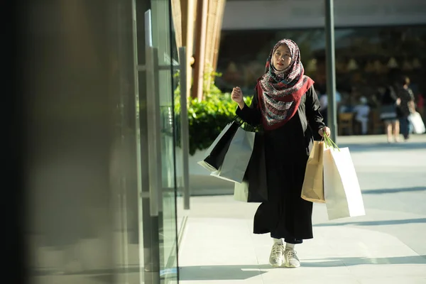 stock image An Asian Muslim woman is carrying a bag of goods that she has been shopping for and buying a lot of products with happy, happy faces.