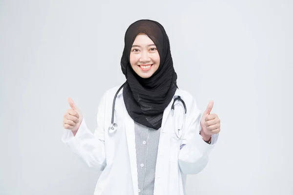 漂亮漂亮的亚裔穆斯林女医生呈大拇指向上的手势 与白人背景隔离 模特是亚裔妇女 — 图库照片