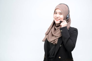 Asyalı Müslüman bir kadın için çalışan bir ofis çalışanı, kulaklıkla mutlu bir yüz ve beyaz arka planda çalışmaya bağlıdır..