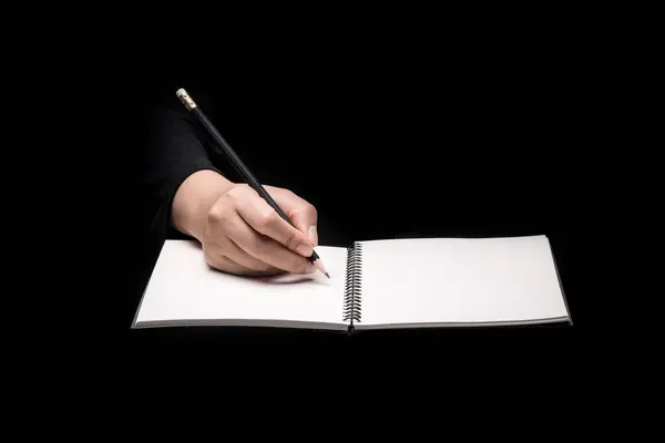 An image of a woman\'s handwriting a note on her notebook, on black background.