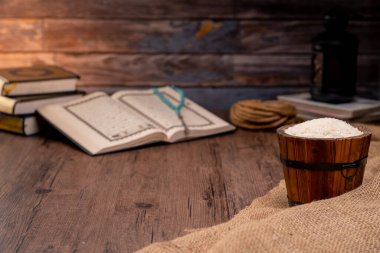 Kutsal Kur 'an ve tahtadan bir sehpanın içindeki tahtadan bir kase pirinç, İslami sadaka kavramı. Müslümanlar yoksullara ve muhtaçlara yardım etsin. Mülkiyet, gelir ve fitne için kavramsal çekim.