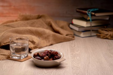 Birçok hurma kabı ve bardak su üzerindedir ve Kur 'an dünyanın dört bir yanındaki ramazan Müslümanları konseptiyle iftar zamanını beklemek için ahşap masalardadır..