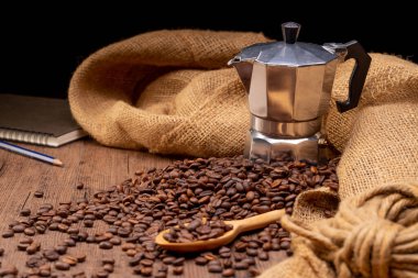 Kahve çekirdekleri, ahşap bir zeminde, sıcak, aydınlık bir atmosferde, koyu bir arkaplanda, fotokopi alanı ile bir araya toplanmış..