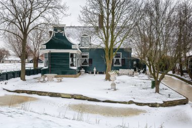Zaandam, Hollanda, 10 Şubat 2021: Hollanda Zaanse Schans, Hollanda 'da donmuş kanal ve geleneksel ahşap evle kış manzarası.