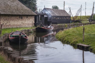 Small canal with its traditional fishing boats, fish smoker in the background.