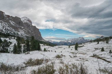 A breathtaking view of the snow-covered Alps with dramatic clouds rolling over rugged peaks. A serene winter scene capturing natures beauty. clipart