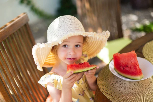 Little girl eating watermelon outside on terrace