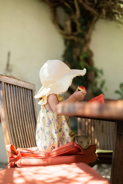 Little girl eating watermelon outside on terrace
