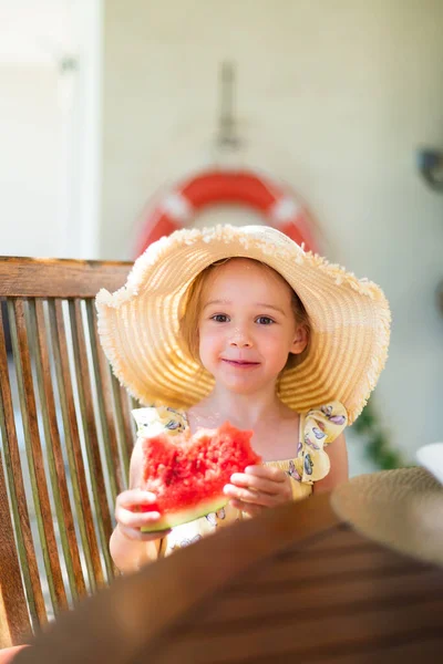 Little girl eating watermelon outside on terrace