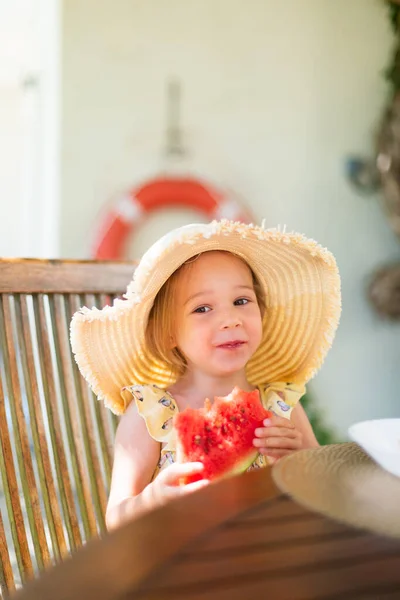 Little girl eating watermelon outside on terrace