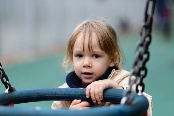 Little girl playing with swings at the playground