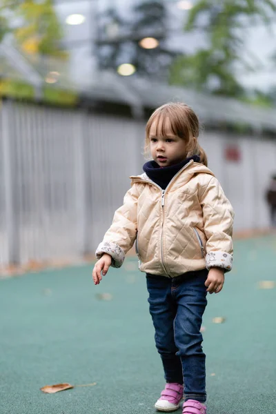 Little girl playing with swings at the playground