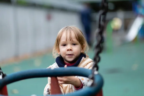 Little girl playing with swings at the playground