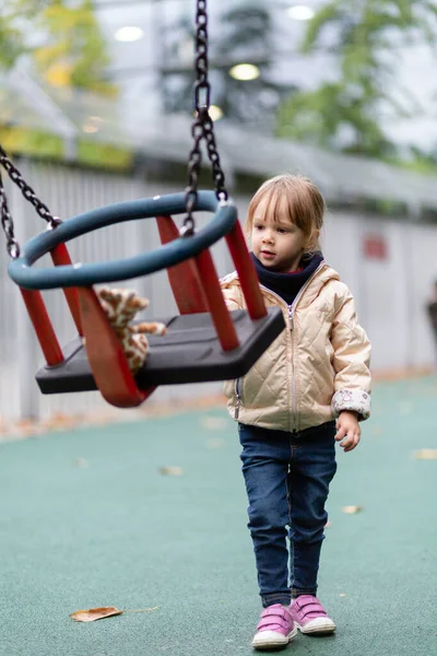 Little girl playing with swings at the playground