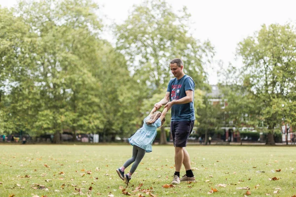 Little girl playing outside in the park with her father