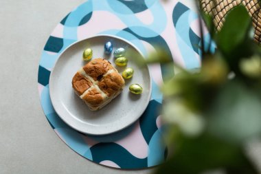 Cross bun and chocolate easter egg with eggs on a white plate