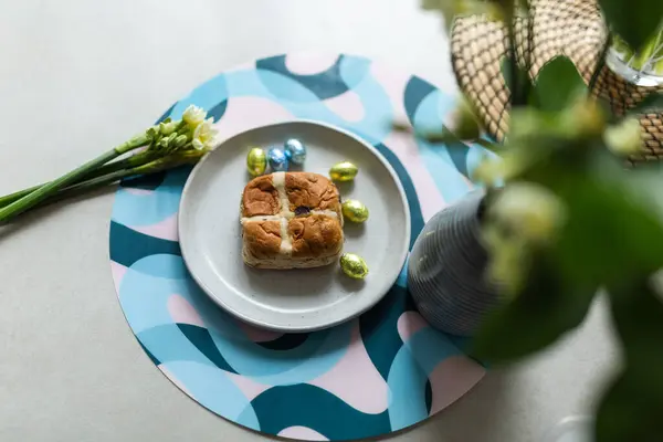 Cross bun and chocolate easter egg with eggs on a white plate