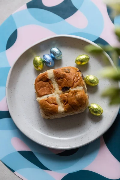 Cross bun and chocolate easter egg with eggs on a white plate
