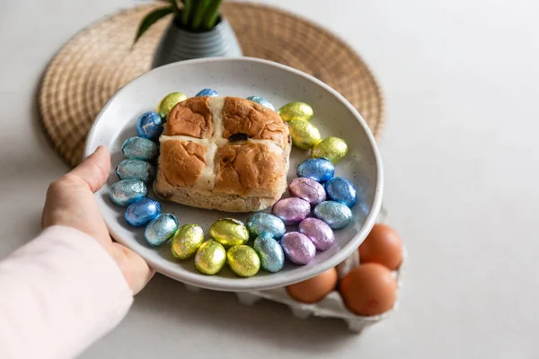 woman holding a plate with cross bun and easter eggs in hand