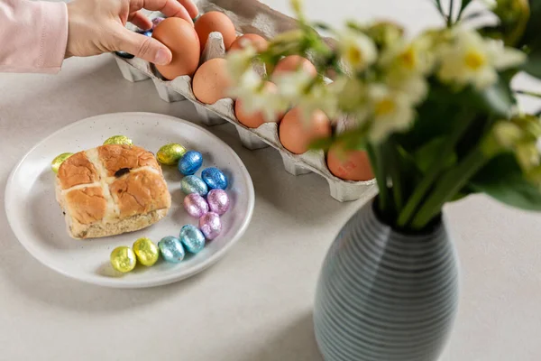 woman holding easter egg in hand and flowers on table