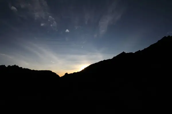 Ngorongoro dağlarının üzerinde gün doğumu gökyüzünü ışık ve gölgeyle boyar..